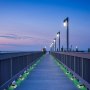 Muelle al anochecer iluminado por luces de entrada solares VEVOR, marcadores de camino de color verde brillante.