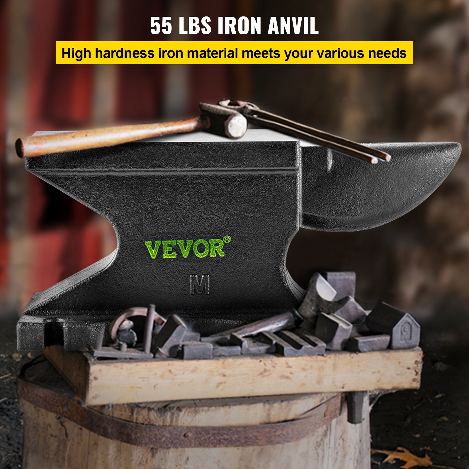 Yunque de hierro fundido VEVOR de 55 libras con martillo, rodeado de piezas de metal sobre una base de madera.