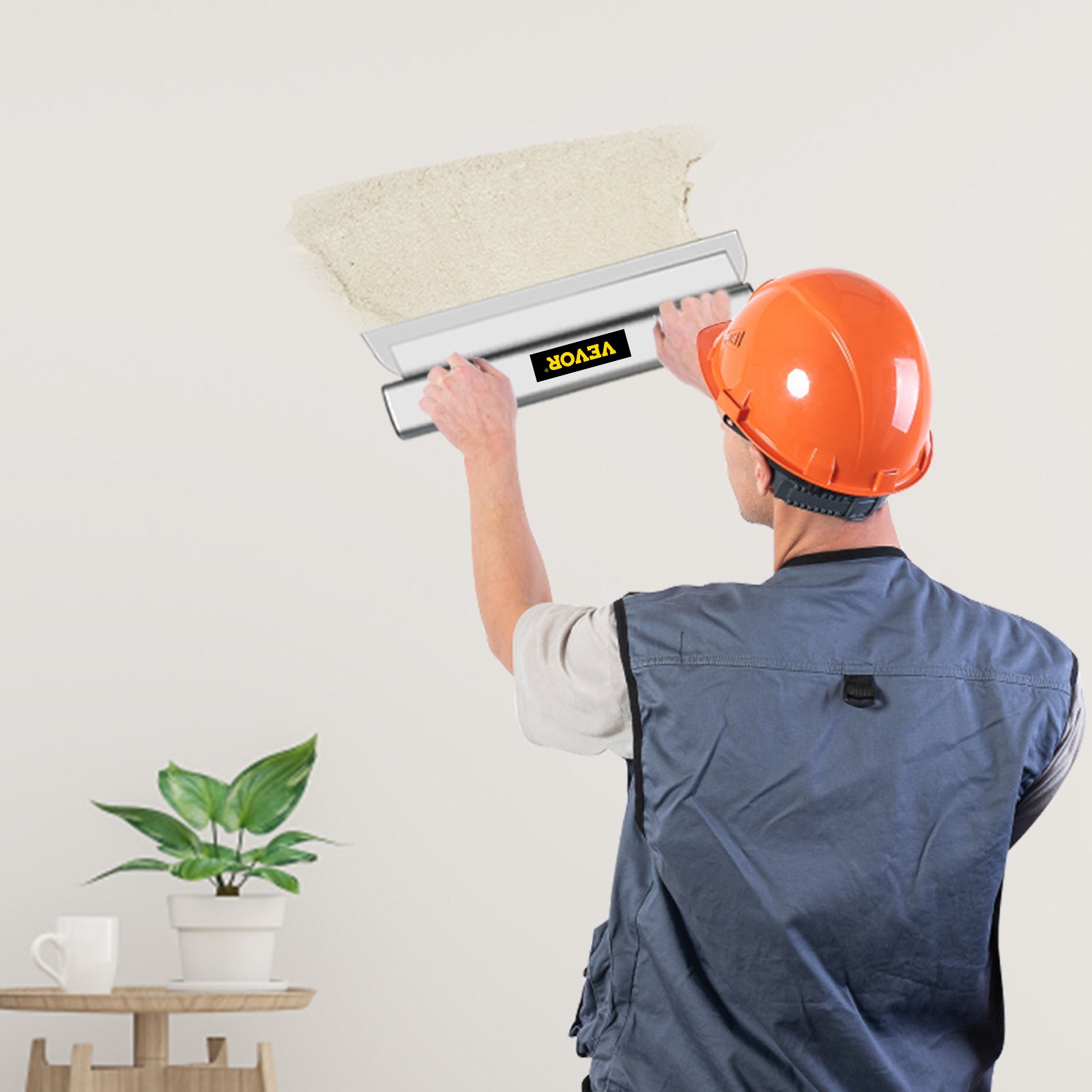 Trabajador que utiliza una cuchilla desnatadora VEVOR para enlucir paredes, con casco naranja y chaleco gris.