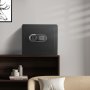 Caja fuerte para el hogar VEVOR negra sobre un estante de madera en una sala de estar minimalista con libros y decoración artística.