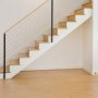 Escalera moderna de madera con barandilla negra y kit de barandilla de cable VEVOR, sobre suelo de madera clara.
