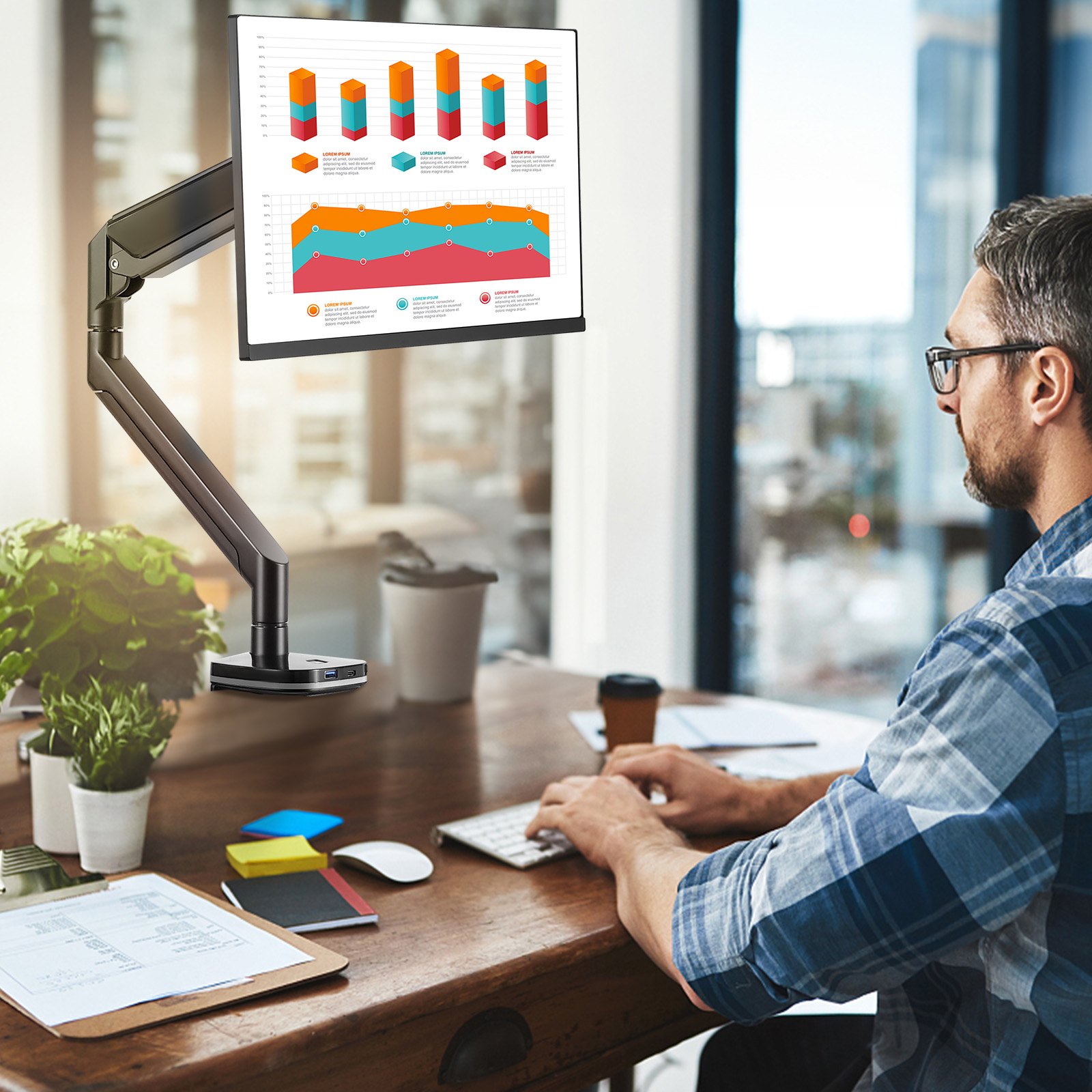 Soporte de monitor VEVOR que sostiene una pantalla que muestra gráficos coloridos en un espacio de oficina luminoso con vista a la ciudad.