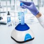 Mezclador de vórtice VEVOR con tubo de ensayo en un entorno de laboratorio, mano enguantada ajustando el tubo.