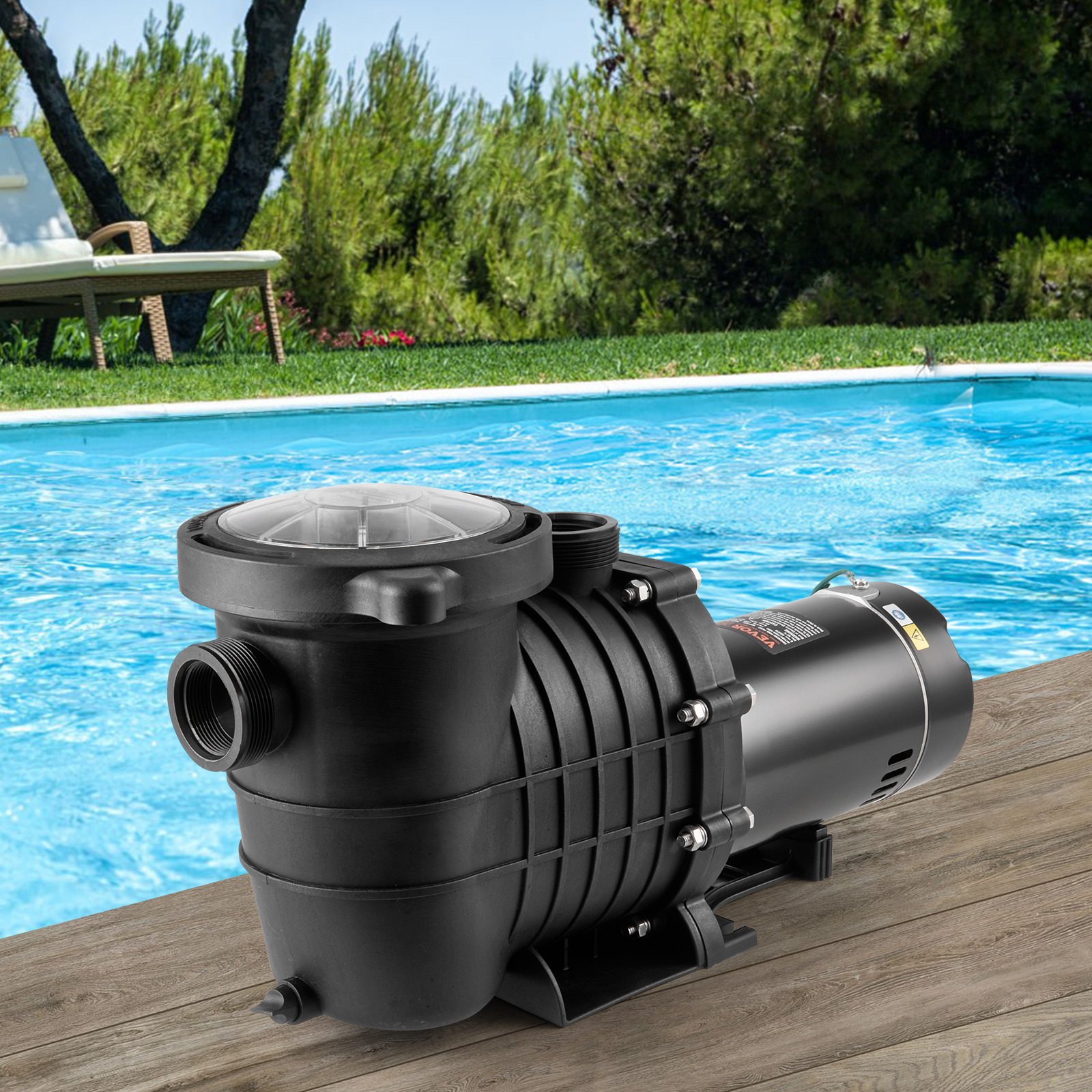 Bomba de piscina VEVOR negra en la cubierta cerca de una piscina azul transparente, rodeada de vegetación.