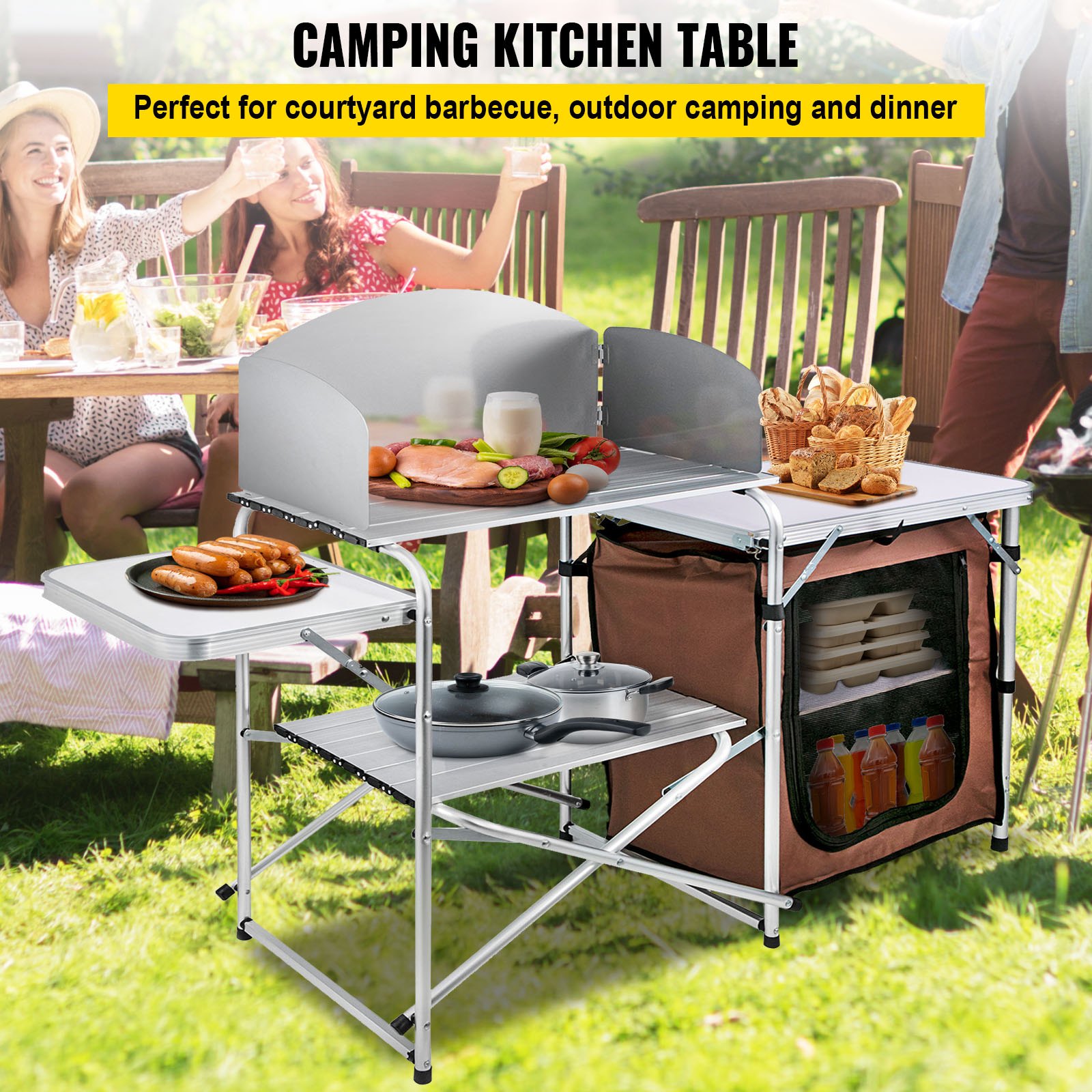 Mesa de cocina para acampar VEVOR instalada al aire libre con comida y bebidas, gente cenando de fondo.
