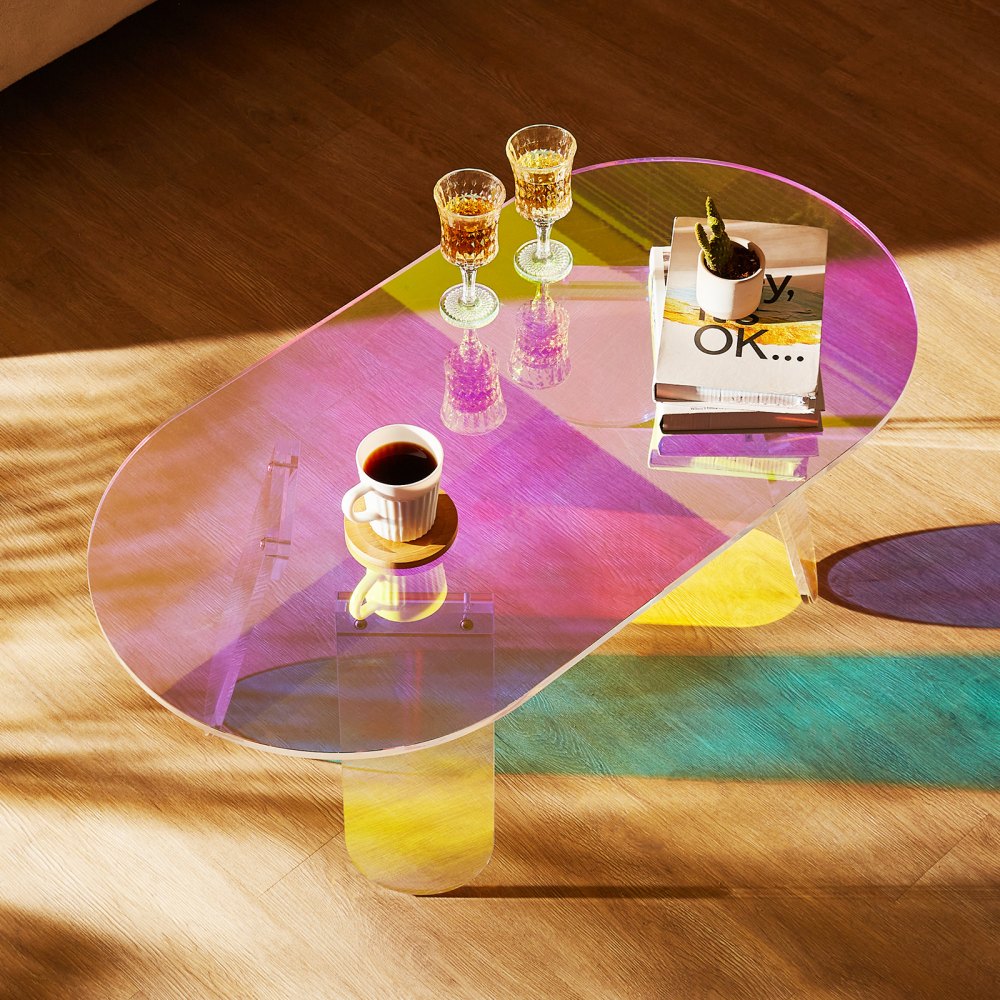 Mesa de centro de acrílico VEVOR con reflejos coloridos, cubierta con vasos, libros y una taza de café.