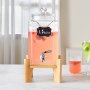 Dispensador de bebidas VEVOR sobre soporte de madera lleno de líquido rosa y fruta, etiquetado 1,5 galones