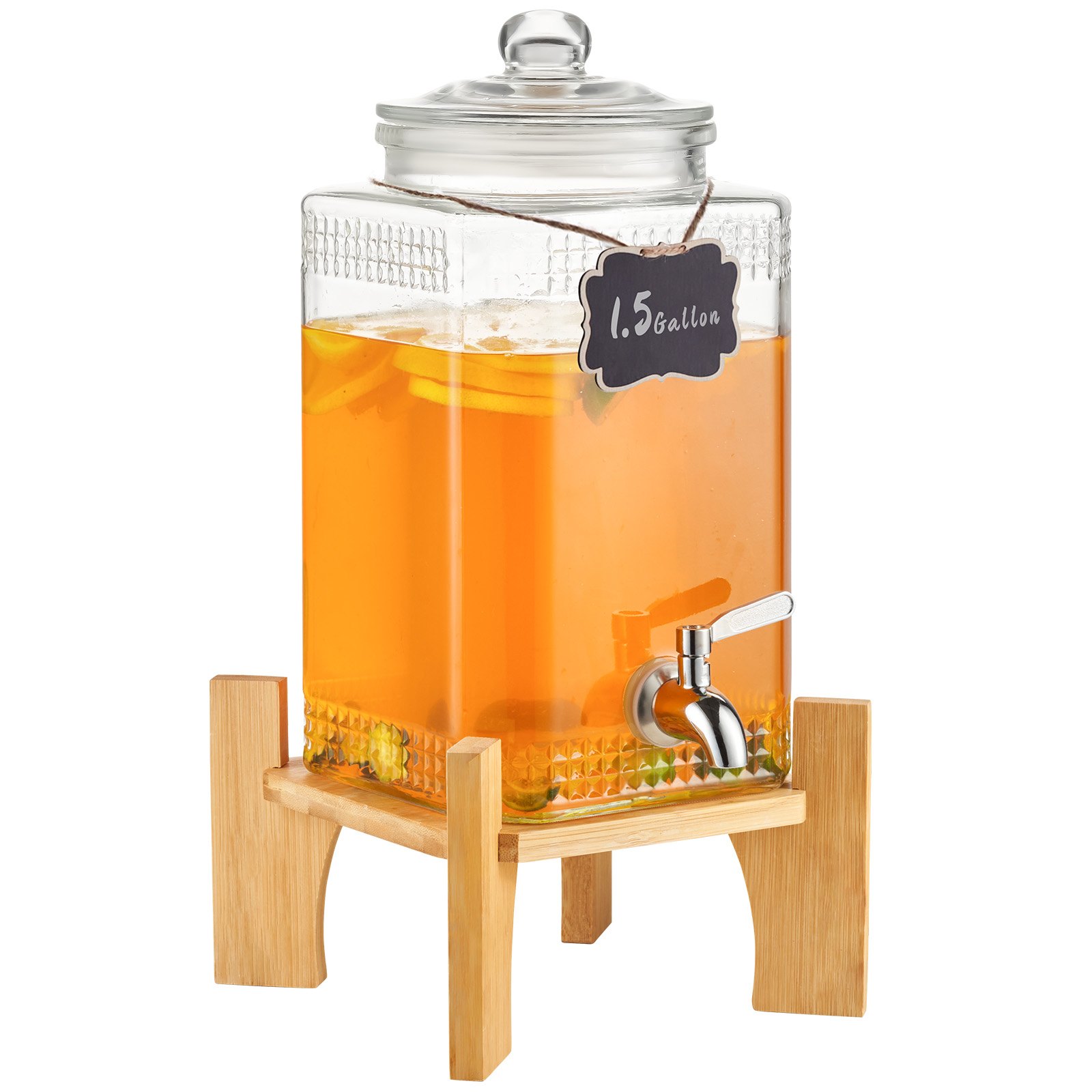 Dispensador de bebidas de vidrio VEVOR lleno de líquido de naranja y rodajas de limón sobre un soporte de madera.