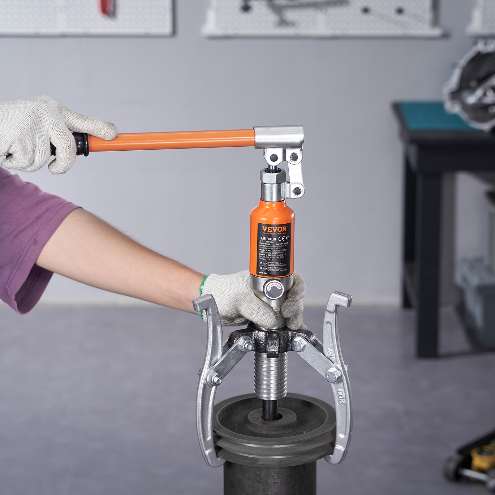 Mecánico que utiliza un extractor de engranajes hidráulico VEVOR para quitar un engranaje de la maquinaria.