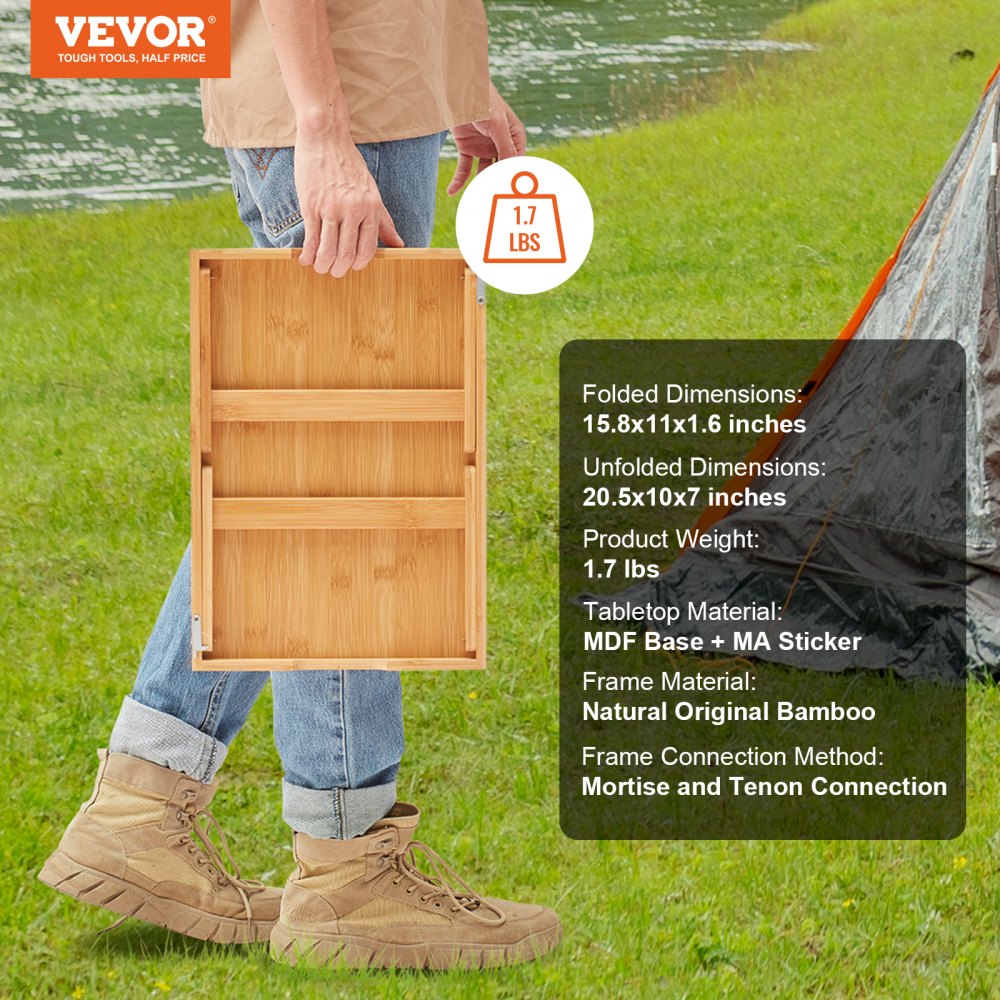 persona sosteniendo una mesa plegable de bambú VEVOR frente a un lago y una tienda de campaña.