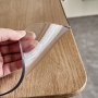 Cubierta de mesa transparente VEVOR levantada a mano sobre el borde de una mesa de madera.