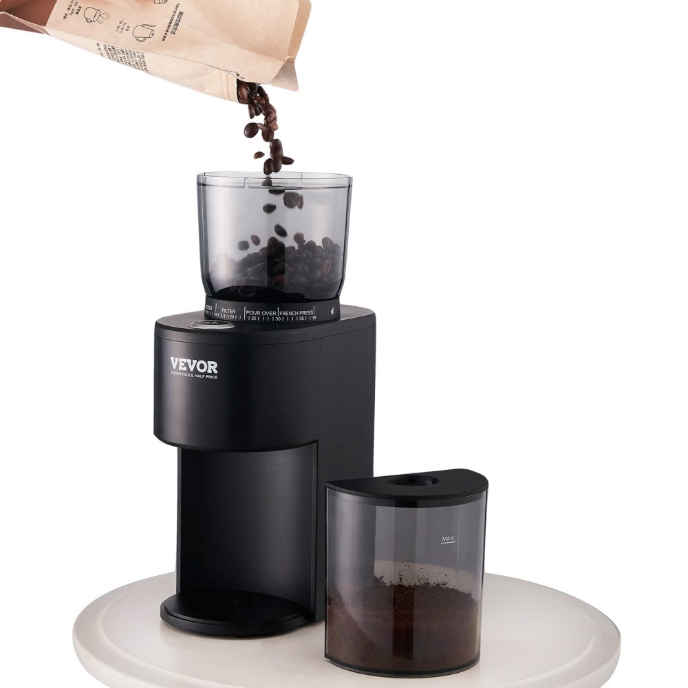 Molinillo de café VEVOR con granos de café vertiéndose en el recipiente superior, colocado sobre una mesa redonda.