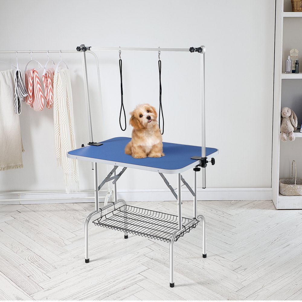 Mesa de aseo para mascotas VEVOR con superficie azul, brazo ajustable y estante de almacenamiento en una habitación moderna.