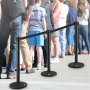 Los puestos de control de multitudes de VEVOR gestionan una cola de personas al aire libre en un día soleado.