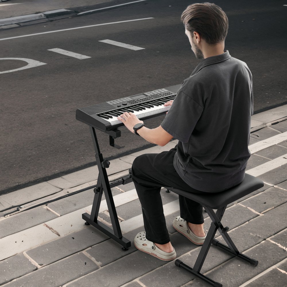 Hombre tocando el teclado en el soporte del teclado de piano VEVOR en la acera de la calle.