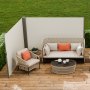 Patio con toldo lateral VEVOR, muebles de mimbre, cojines naranjas y terraza de madera.