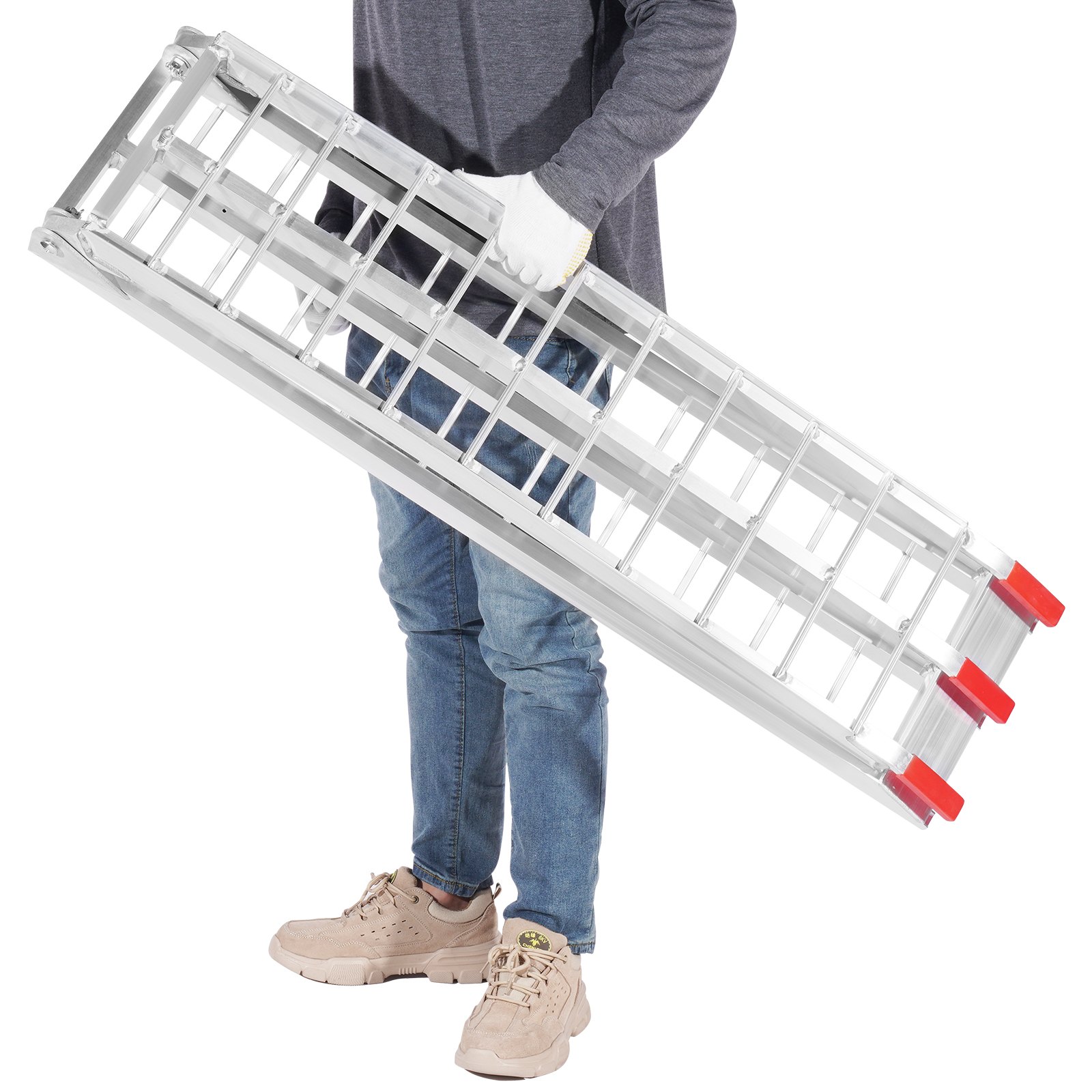 Persona sosteniendo rampas de carga de aluminio plegables VEVOR con tapas rojas, vestida con jeans azules casuales y zapatos beige.