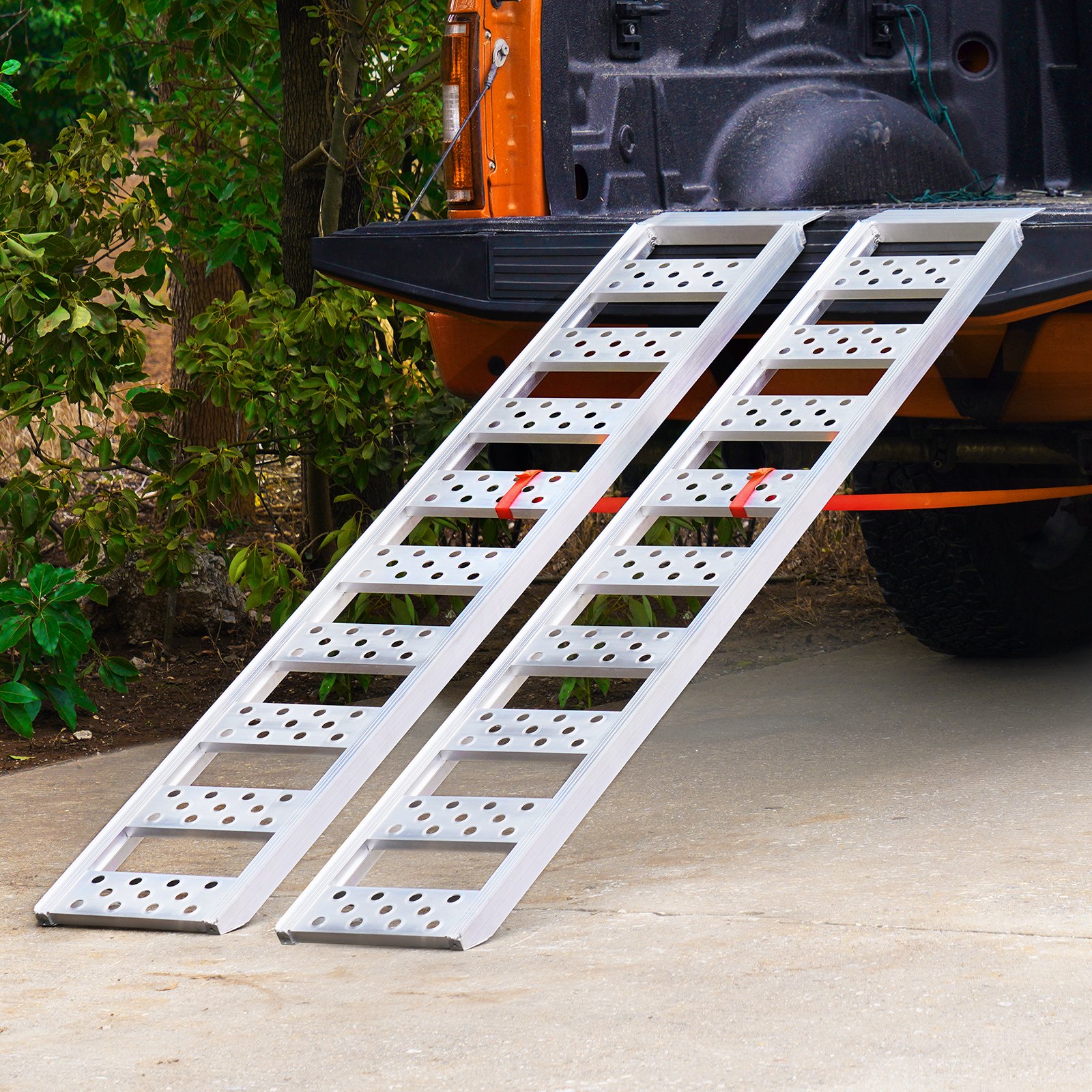 Rampas de carga dobles de aluminio VEVOR que se extienden desde la parte trasera de una camioneta hasta un camino de entrada de concreto.