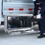 worker placing tools into a VEVOR underbody truck box next to a vehicle storage compartment.