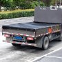 Kiepwagen met zwart VEVOR-kiepwagengaaszeil geparkeerd op het parkeerterrein, groene struiken op de achtergrond.