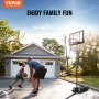 family playing basketball in front of a garage with a VEVOR basketball hoop under a clear sky.