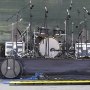 stage setup with microphones, drum set, cables, and VEVOR cable protector ramp in front.