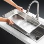 washing a VEVOR hotel pan under a modern kitchen faucet in a stainless steel sink.