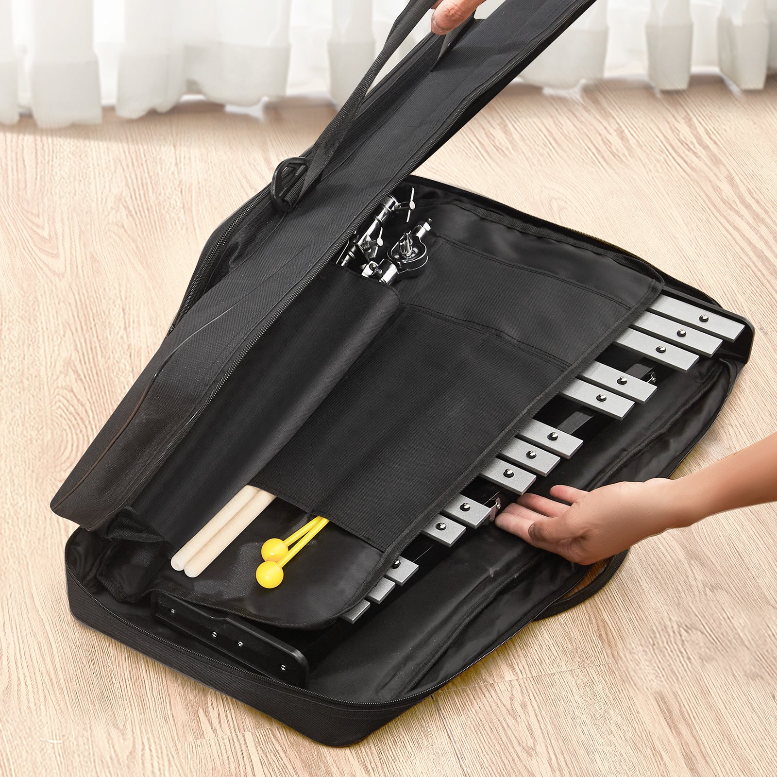 hands organizing a VEVOR glockenspiel kit in a black carrying case on a wooden floor.
