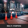 three VEVOR traffic cones on a city sidewalk at night with skyscrapers in the background.