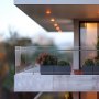 modern balcony with glass railing using VEVOR glass clamp, featuring potted plants and soft lighting.