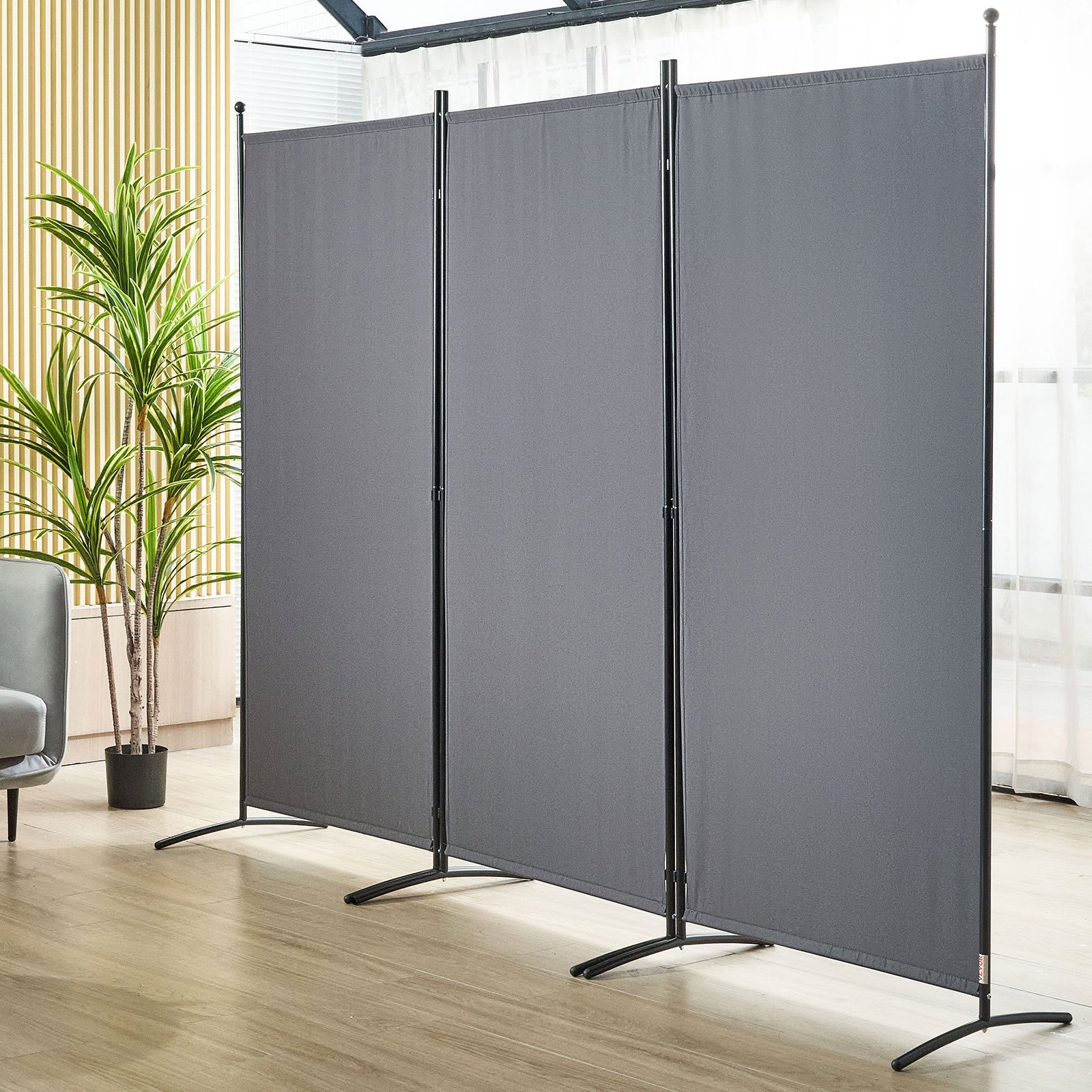 VEVOR room divider in a modern living space with gray panels, black frames, indoor plant, and light wood flooring.