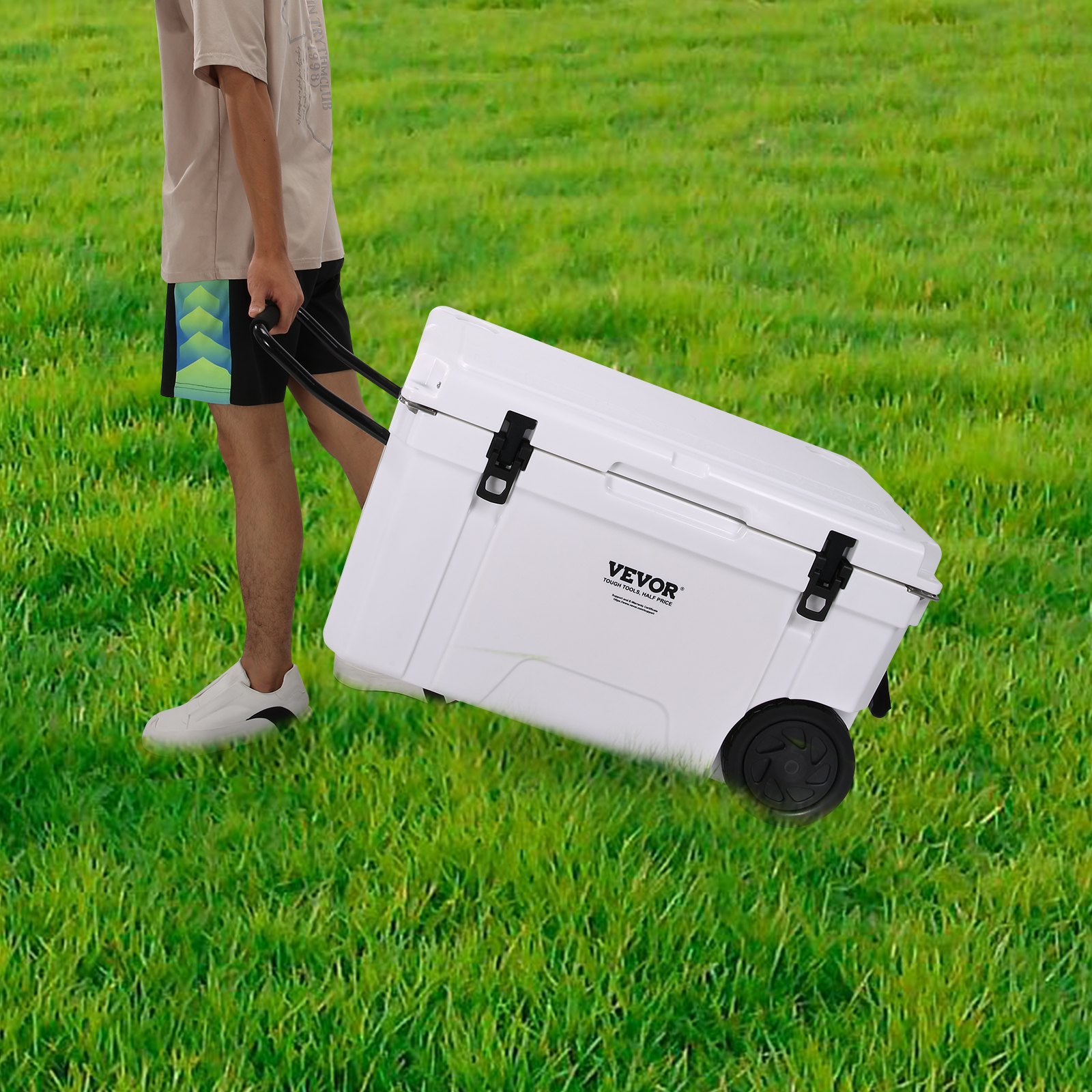 person pulling white VEVOR insulated portable cooler on wheels across vibrant green grass.