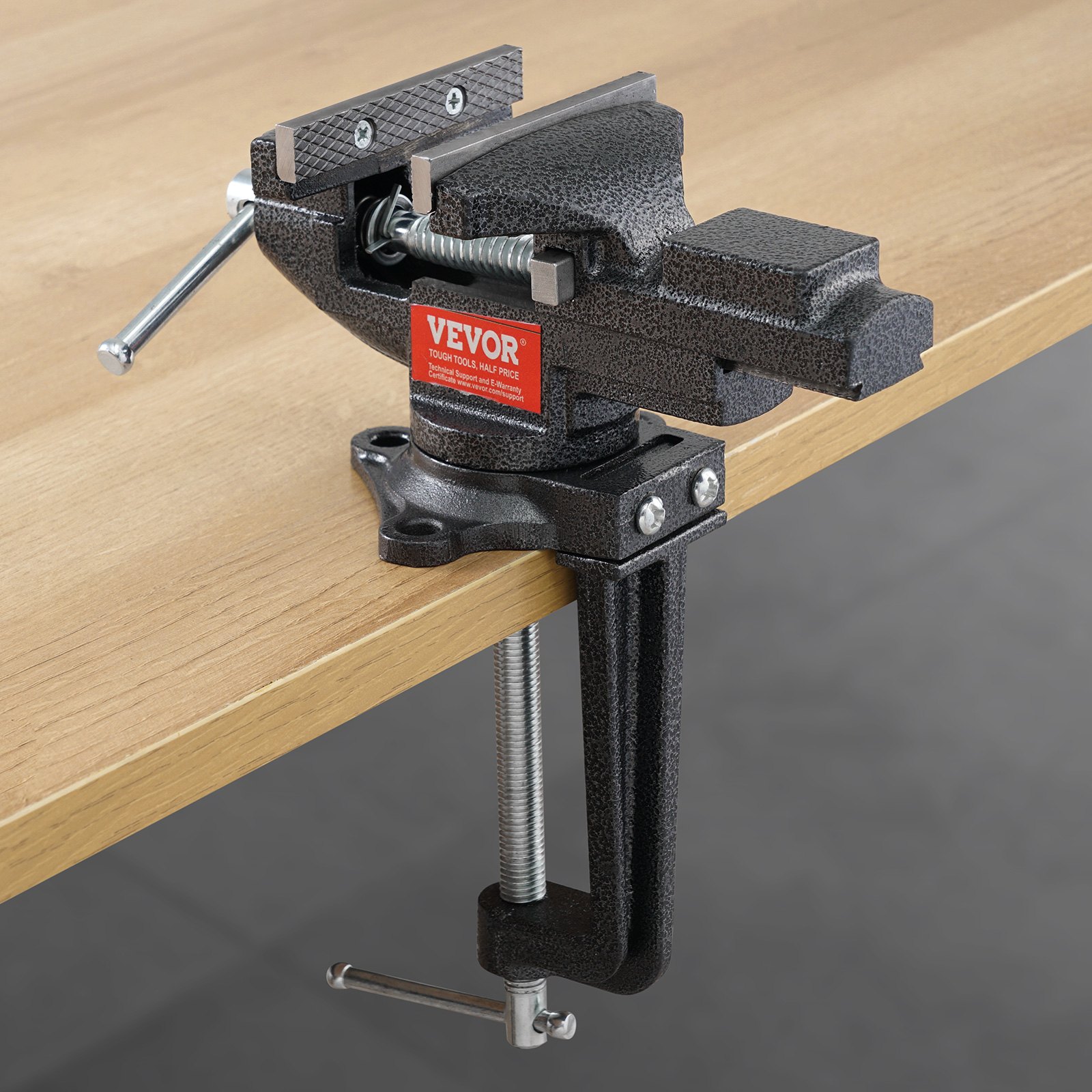 VEVOR bench vise clamped to a wooden workbench, showcasing its grip and sturdy construction.