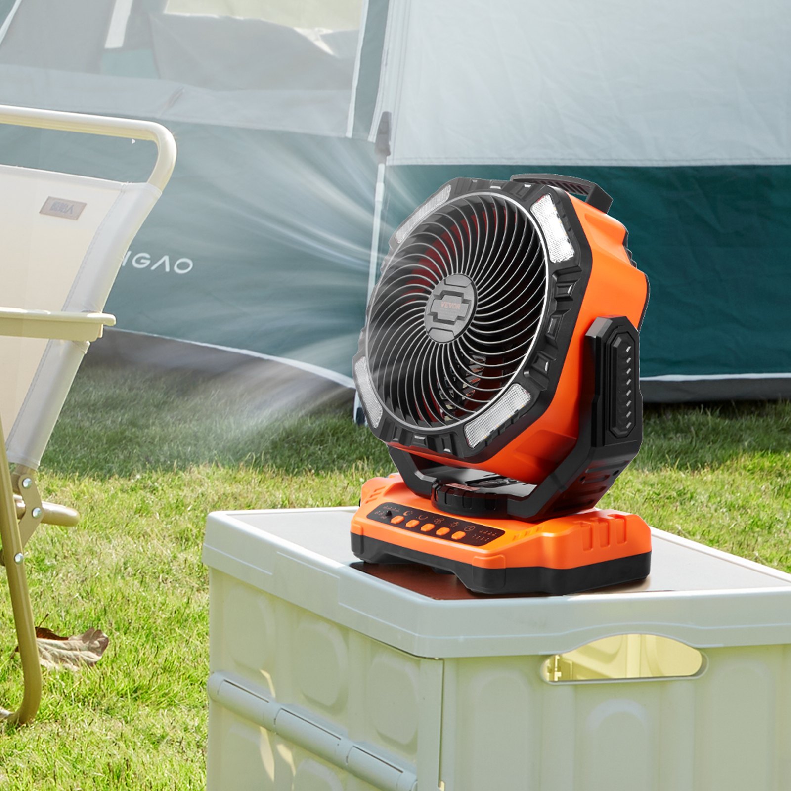 VEVOR portable fan on a table outside a green tent, providing a refreshing breeze in a camping setup.