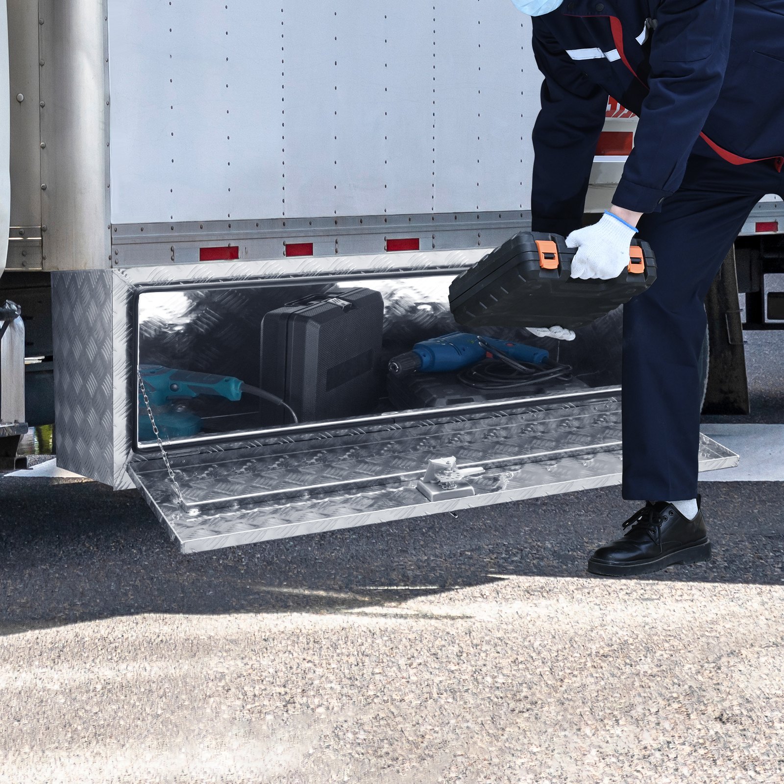 worker placing tools inside VEVOR underbody truck box mounted on a truck, showcasing storage capacity.