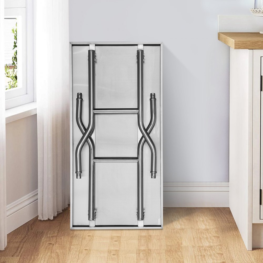 folded VEVOR commercial worktable leaning against a kitchen wall, next to the window.
