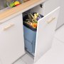under-sink VEVOR pull-out trash can with food waste, surrounded by white cabinetry with gold handles.