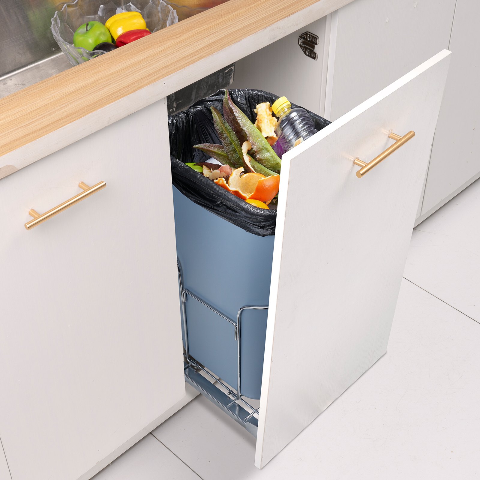 under-sink VEVOR pull-out trash can with food waste, surrounded by white cabinetry with gold handles.