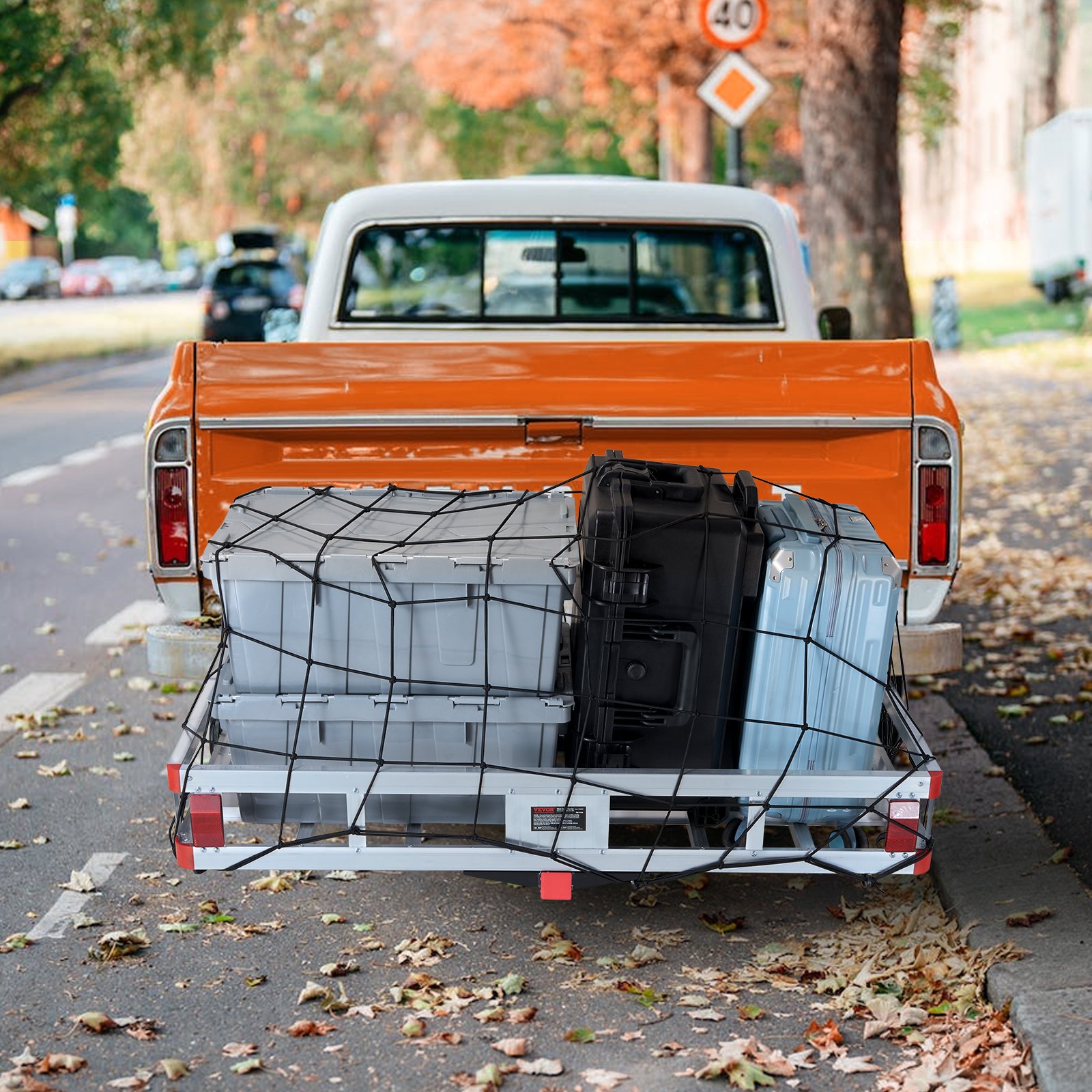 orange truck with loaded VEVOR hitch cargo carrier secured by a net, parked on a leafy street in autumn.