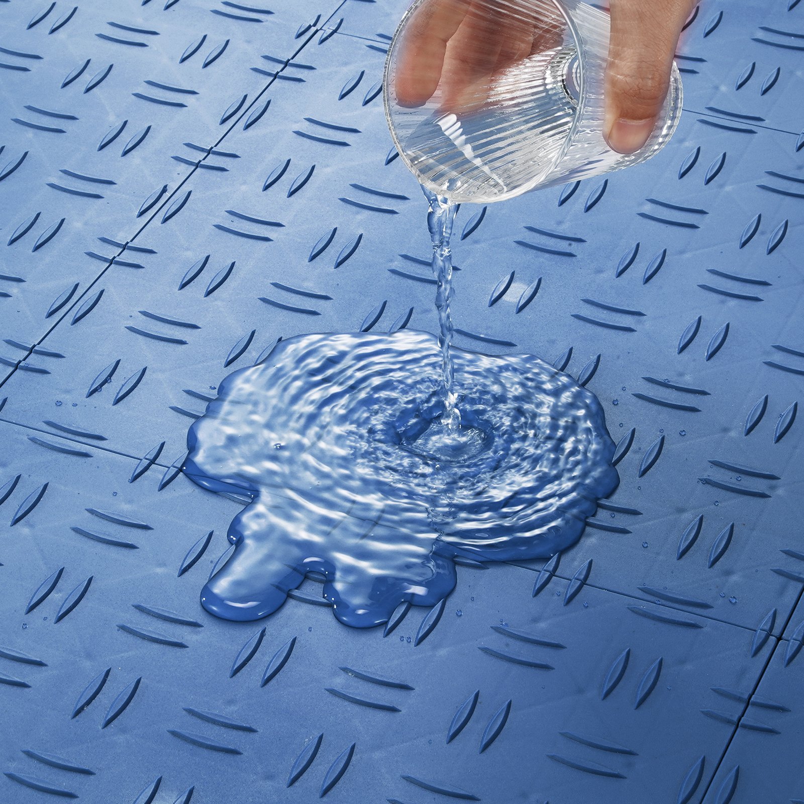 pouring water on blue VEVOR garage tiles showing water resistance and textured surface.