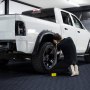 mechanic working on a white truck in a garage with VEVOR garage tiles.