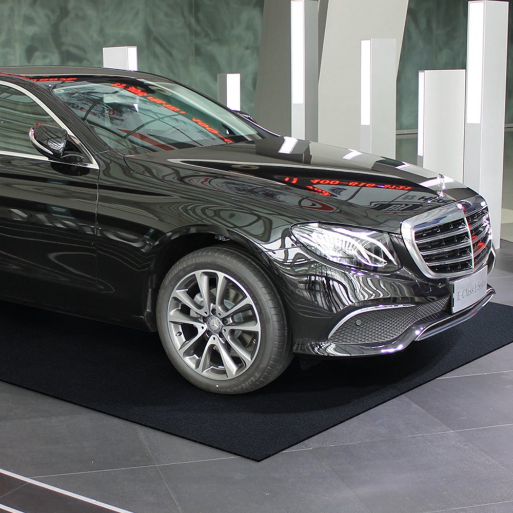 black car parked on a VEVOR garage floor mat in a modern showroom with reflective surfaces.