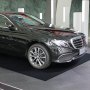 black car parked on a VEVOR garage floor mat in a modern showroom with reflective surfaces.