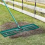 VEVOR lawn leveling rake used to spread soil over a grass lawn, next to a wooden fence.