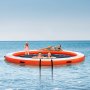 VEVOR inflatable floating dock with people relaxing and swimming in the ocean under clear blue sky.