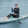 person seated on VEVOR inflatable paddle board in water, holding a paddle, in black wet suit.