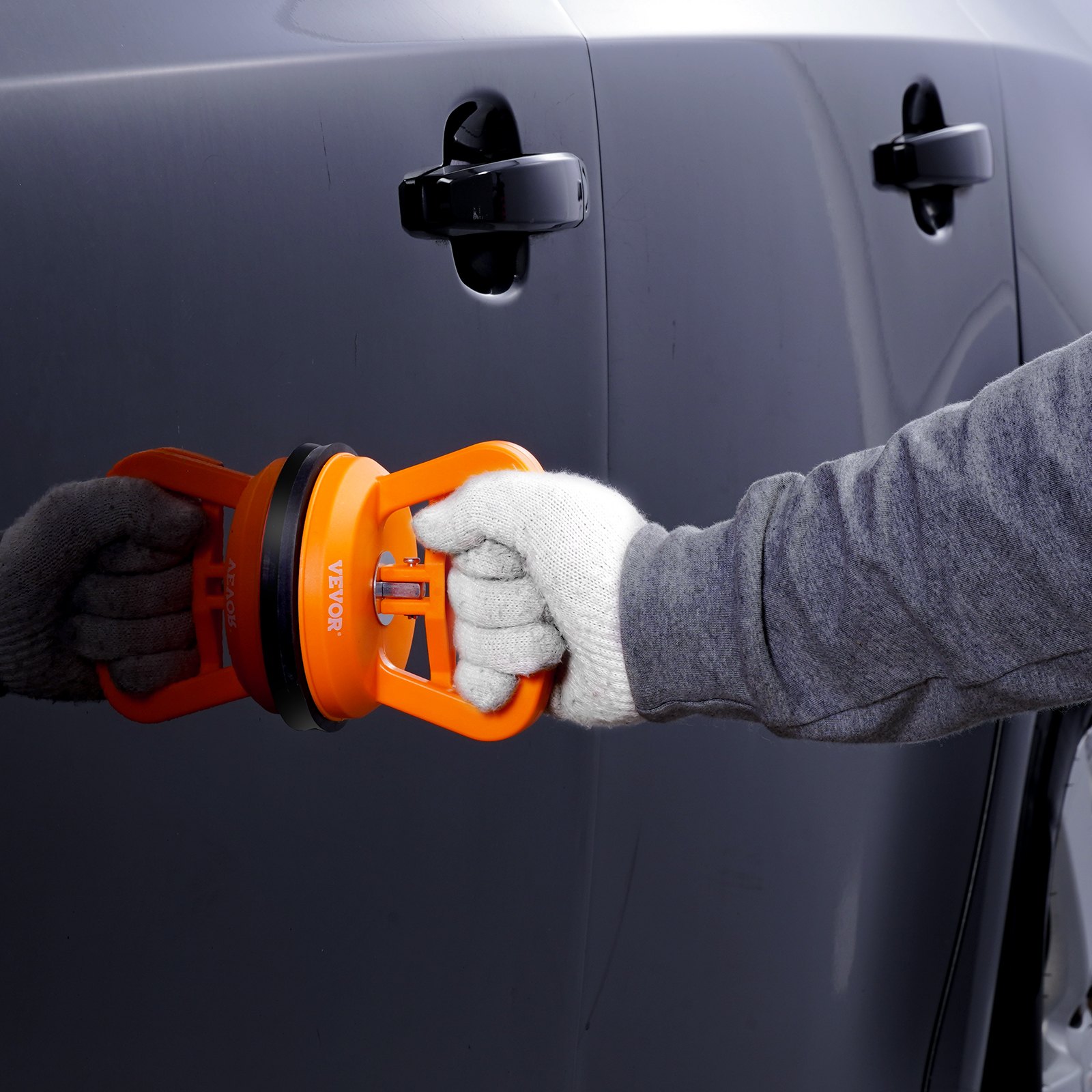 removing dent from car door using VEVOR dent removal kit with orange suction cup tool and gloved hands
