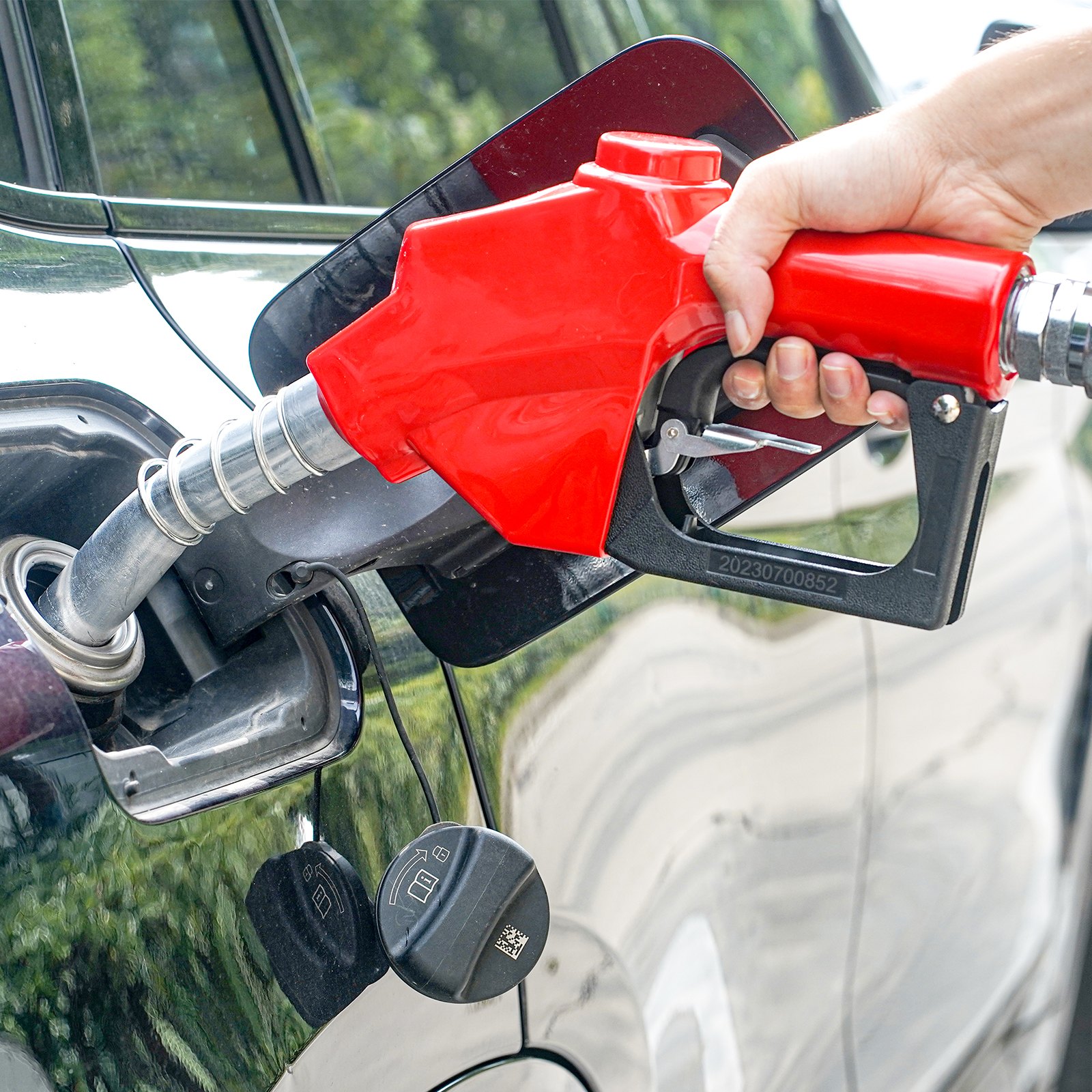 car being refueled with a red nozzle, highlighting the VEVOR fuel hose reel effectiveness.