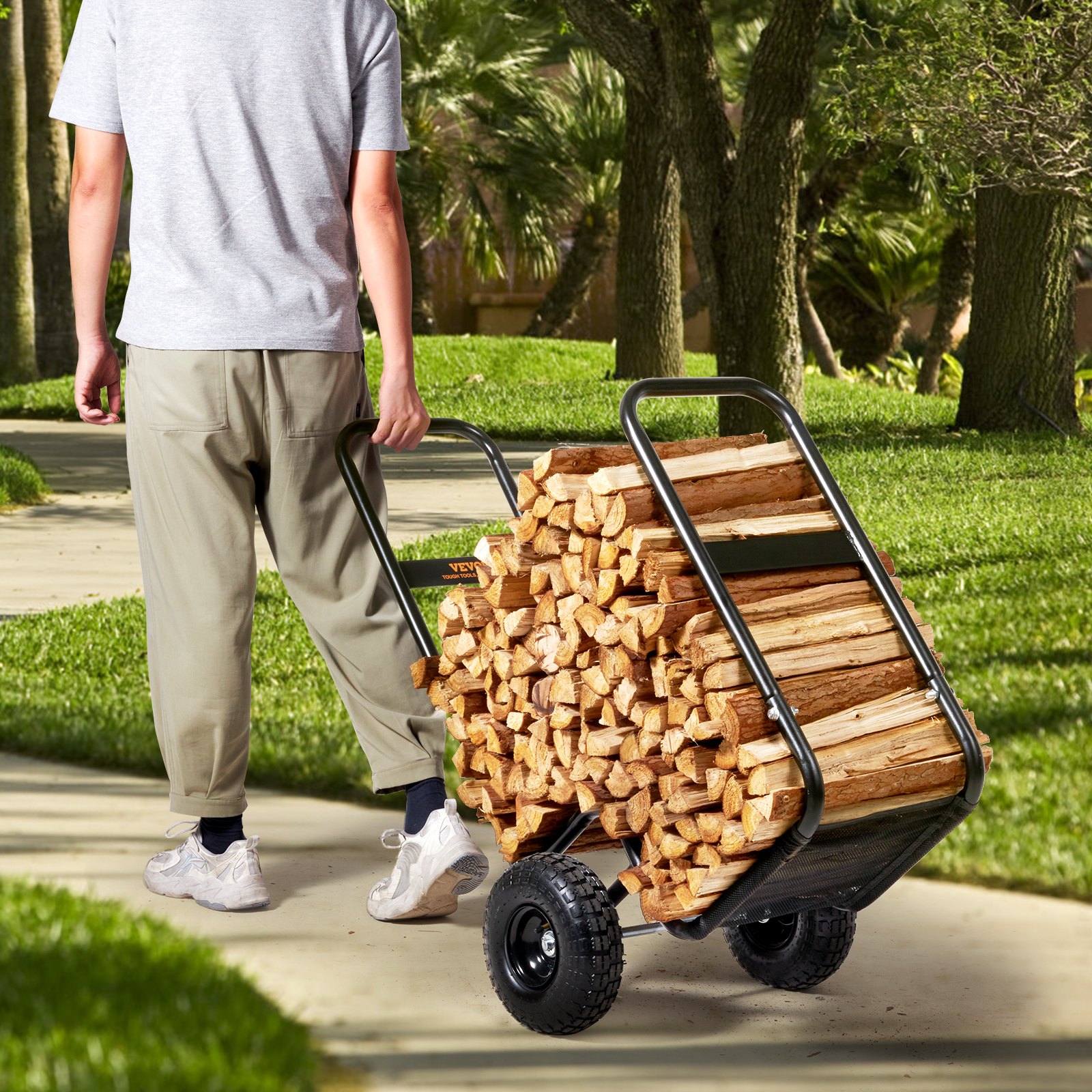 man transporting firewood with a VEVOR firewood log cart in a lush green park.