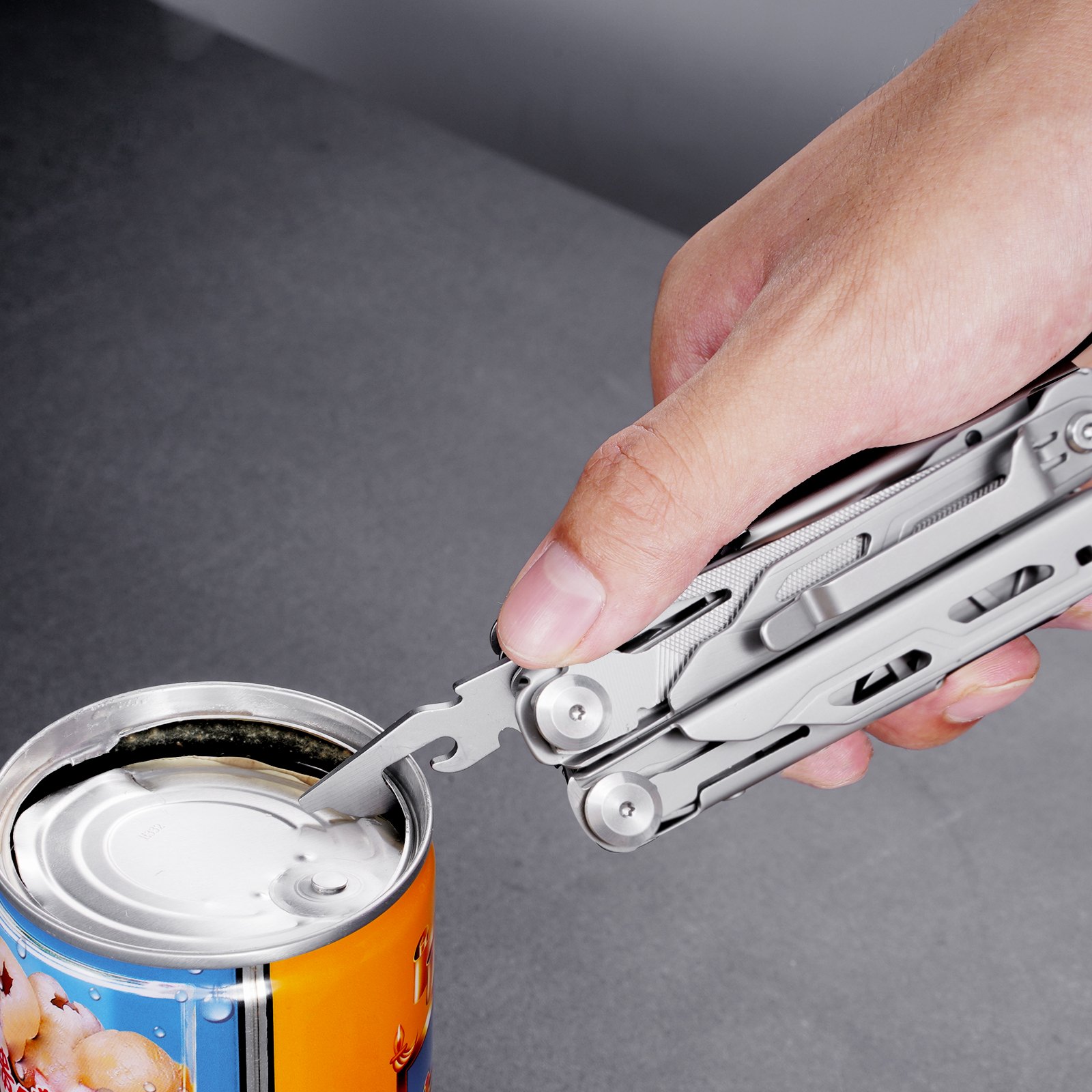 hand using VEVOR multitool pliers to open a can on a grey surface.